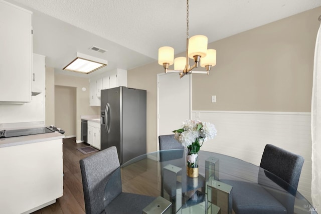 dining room with dark wood-type flooring, a chandelier, visible vents, and a textured ceiling