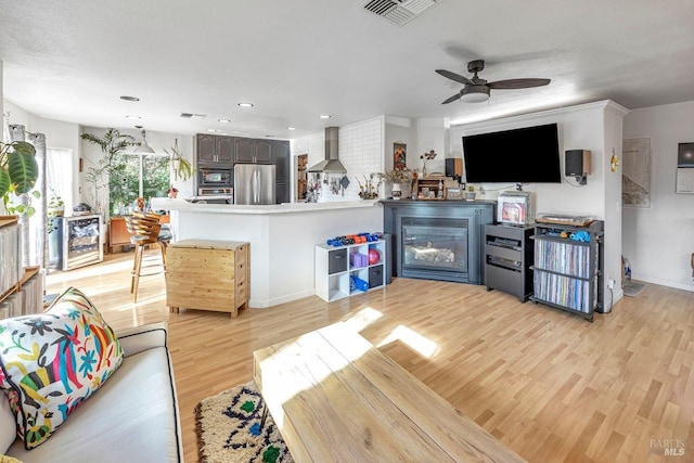 living room featuring wine cooler, light hardwood / wood-style flooring, and ceiling fan