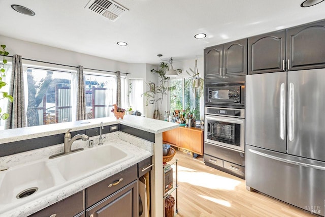 kitchen featuring sink, dark brown cabinets, stainless steel appliances, and light wood-type flooring