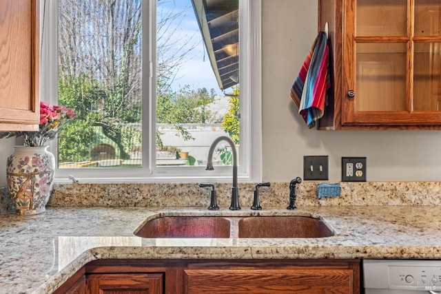 interior details with sink, light stone counters, and white dishwasher