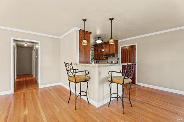 kitchen with crown molding, kitchen peninsula, a breakfast bar area, and light hardwood / wood-style flooring