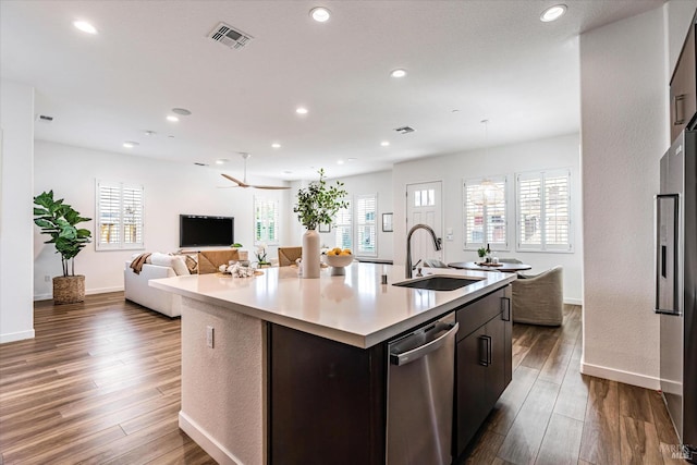 kitchen featuring a center island with sink, open floor plan, stainless steel appliances, light countertops, and a sink