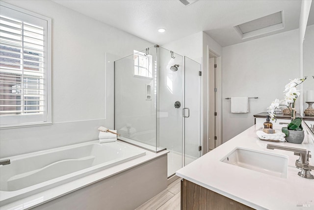 bathroom featuring double vanity, a stall shower, wood finished floors, a garden tub, and a sink