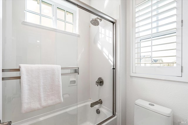 bathroom with bath / shower combo with glass door and toilet