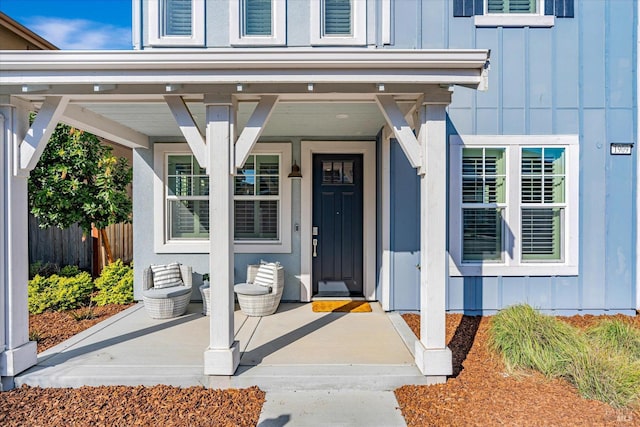 entrance to property featuring board and batten siding and fence