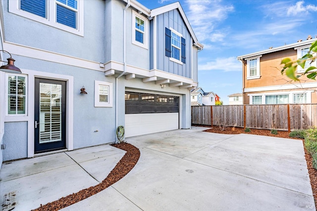 exterior space with an attached garage, fence, driveway, stucco siding, and board and batten siding