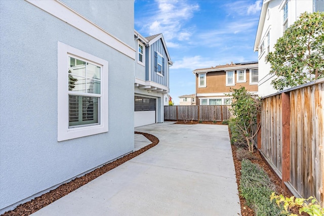 view of patio / terrace featuring concrete driveway, a fenced backyard, and an attached garage