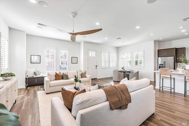 living area with light wood-style floors, visible vents, a wealth of natural light, and recessed lighting