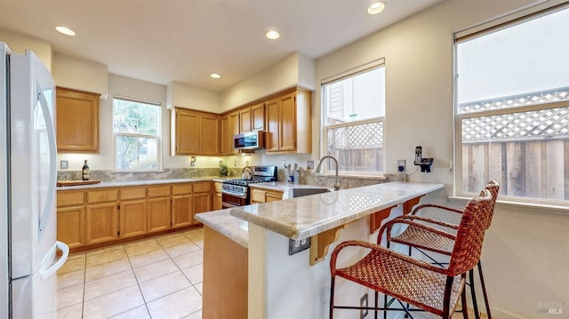 kitchen with sink, a breakfast bar area, kitchen peninsula, and appliances with stainless steel finishes