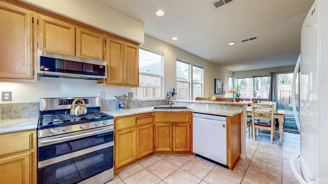 kitchen featuring stainless steel appliances, sink, light tile patterned floors, and kitchen peninsula