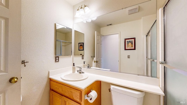 bathroom with vanity, a shower with shower door, and toilet