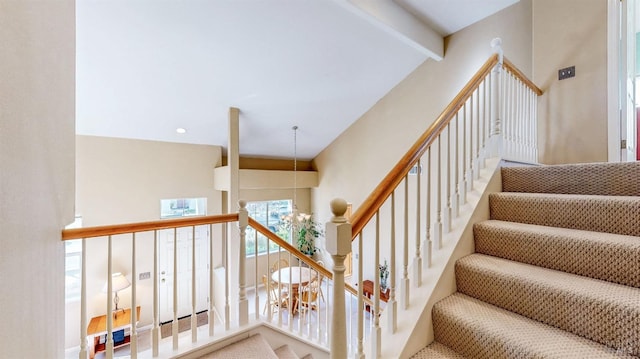 stairway with beamed ceiling and a chandelier