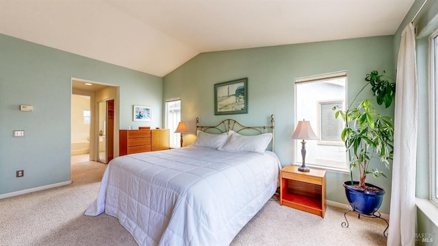 bedroom with light colored carpet, lofted ceiling, ensuite bath, and multiple windows