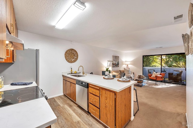 kitchen featuring stainless steel appliances, kitchen peninsula, sink, and a textured ceiling