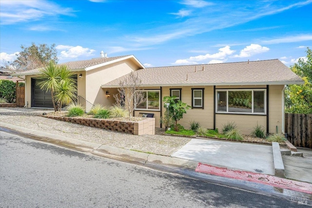 ranch-style home featuring concrete driveway, an attached garage, fence, and roof with shingles