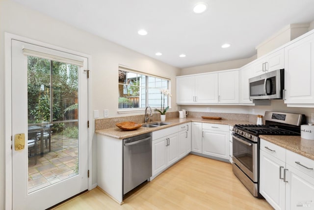 kitchen featuring white cabinetry, sink, light wood-type flooring, and appliances with stainless steel finishes