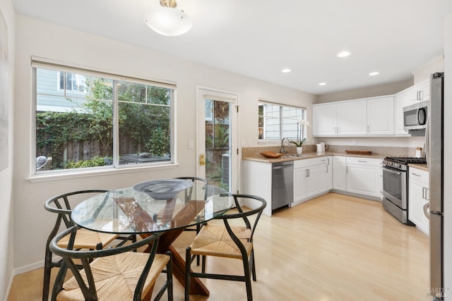 kitchen with stainless steel appliances, light hardwood / wood-style floors, sink, and white cabinets