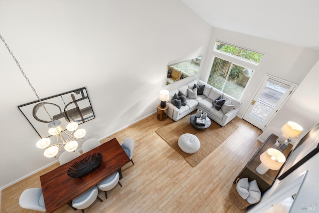 living room with a notable chandelier, light hardwood / wood-style floors, and high vaulted ceiling