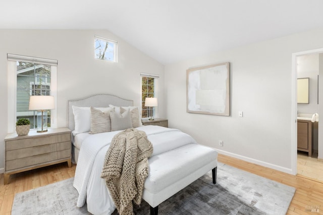 bedroom featuring lofted ceiling, ensuite bathroom, and light wood-type flooring