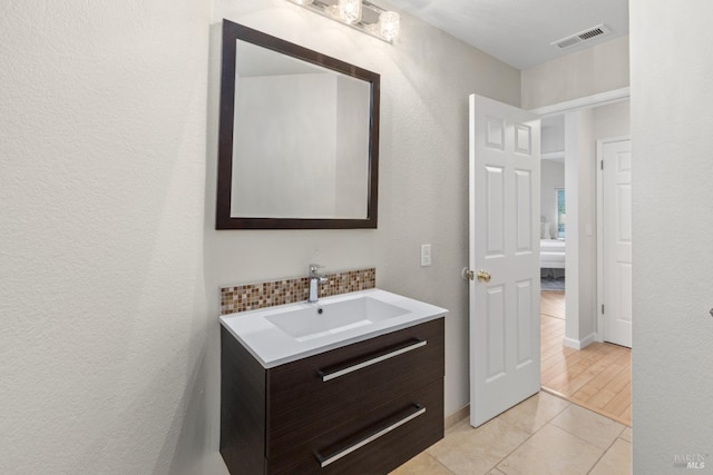 bathroom featuring tile patterned floors, vanity, and decorative backsplash