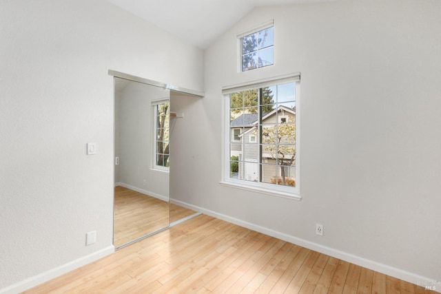 unfurnished room featuring lofted ceiling and light hardwood / wood-style floors