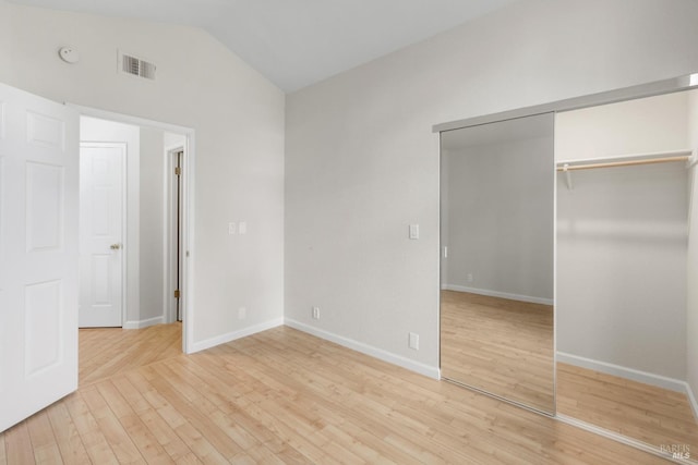 unfurnished bedroom featuring lofted ceiling, light wood-type flooring, and a closet