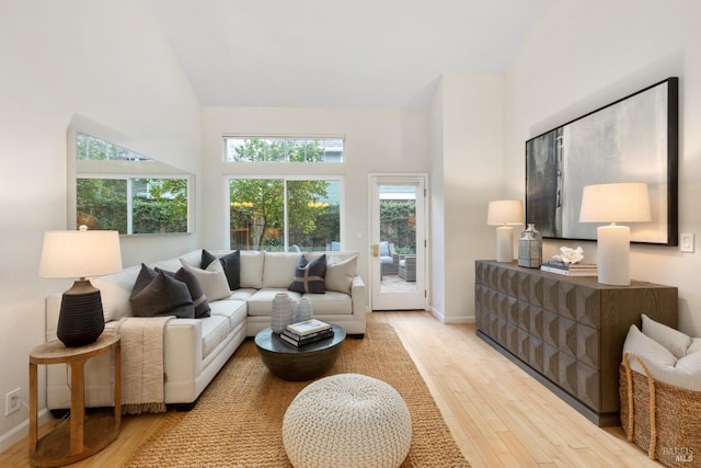 living room featuring high vaulted ceiling and light hardwood / wood-style floors