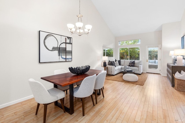 dining area featuring an inviting chandelier, high vaulted ceiling, and light hardwood / wood-style floors