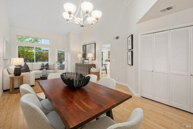 dining space featuring a notable chandelier, high vaulted ceiling, and light wood-type flooring