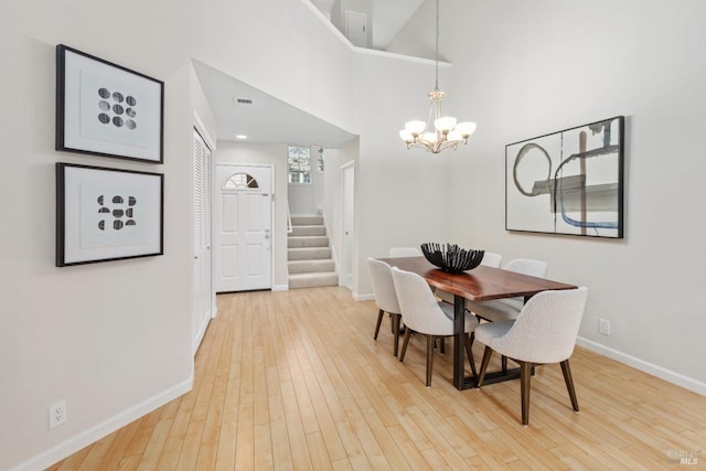 dining room with an inviting chandelier, a towering ceiling, and wood-type flooring