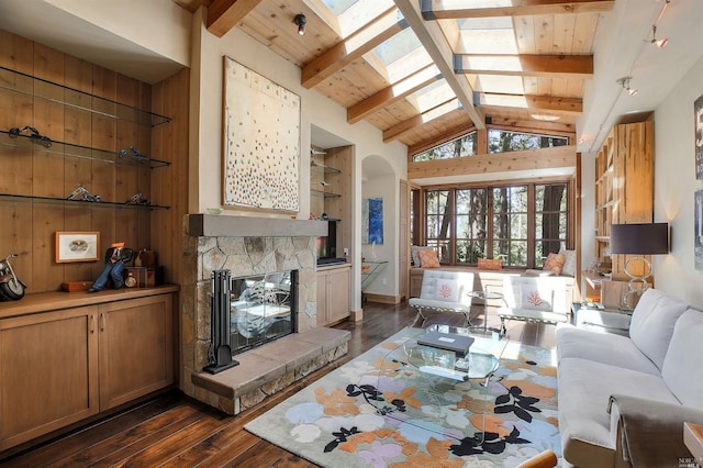 living room featuring dark hardwood / wood-style floors, built in features, a fireplace, a skylight, and beamed ceiling