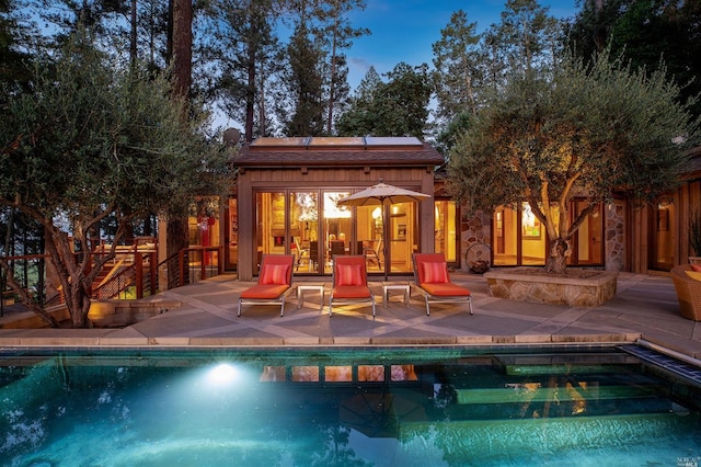 pool at dusk featuring an outdoor structure and a patio