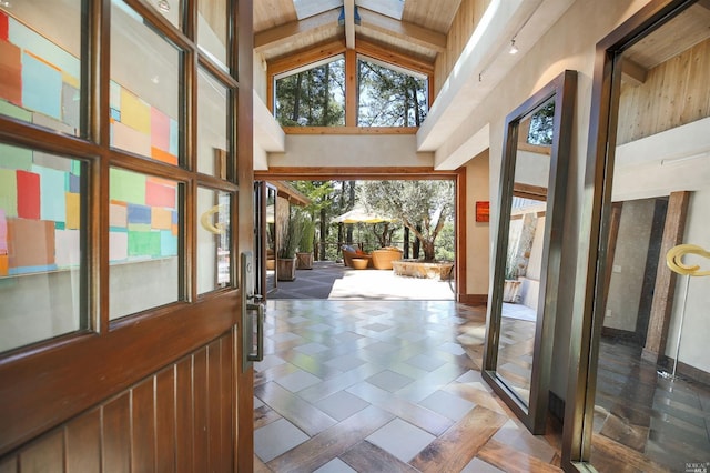 doorway with beamed ceiling and high vaulted ceiling