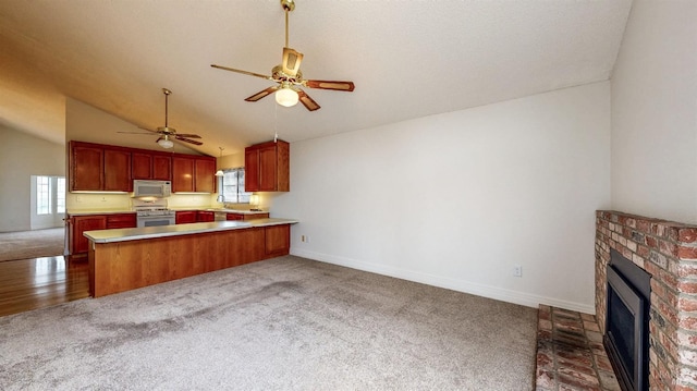 kitchen featuring lofted ceiling, a brick fireplace, kitchen peninsula, dark carpet, and white appliances