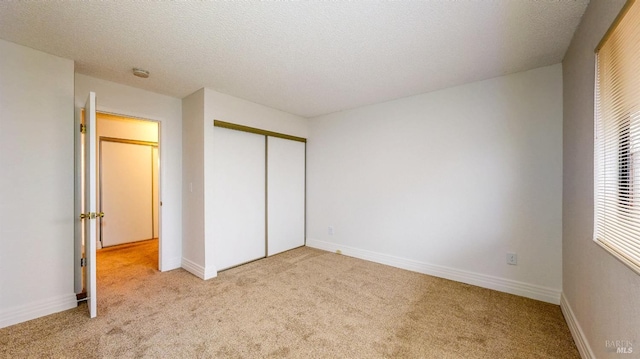 unfurnished bedroom with light colored carpet, a closet, and a textured ceiling