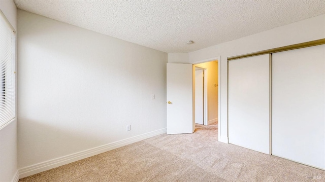 unfurnished bedroom with light colored carpet, a closet, and a textured ceiling