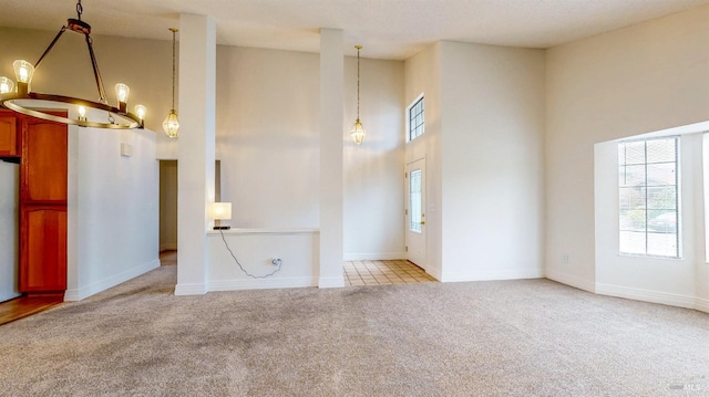 interior space featuring an inviting chandelier, a towering ceiling, and light colored carpet