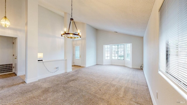 spare room with light carpet, a textured ceiling, high vaulted ceiling, and a chandelier