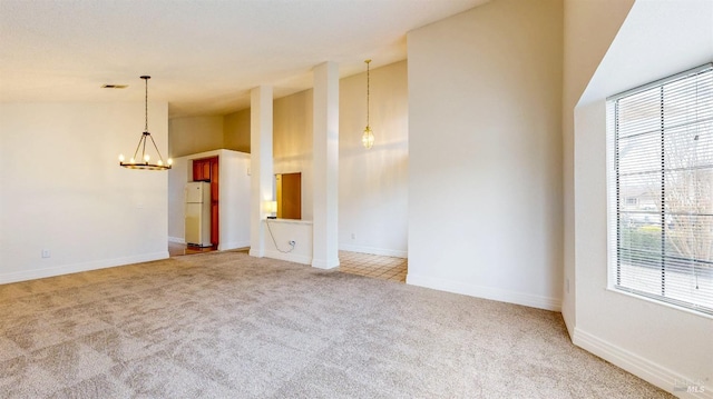 spare room with vaulted ceiling, a healthy amount of sunlight, light carpet, and an inviting chandelier