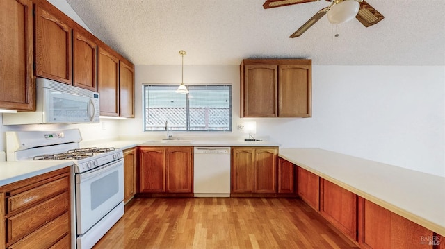 kitchen featuring pendant lighting, sink, light wood-type flooring, white appliances, and a textured ceiling