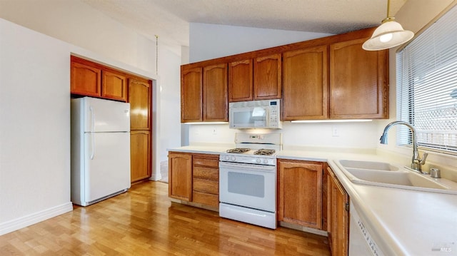 kitchen featuring sink, decorative light fixtures, vaulted ceiling, white appliances, and light hardwood / wood-style floors