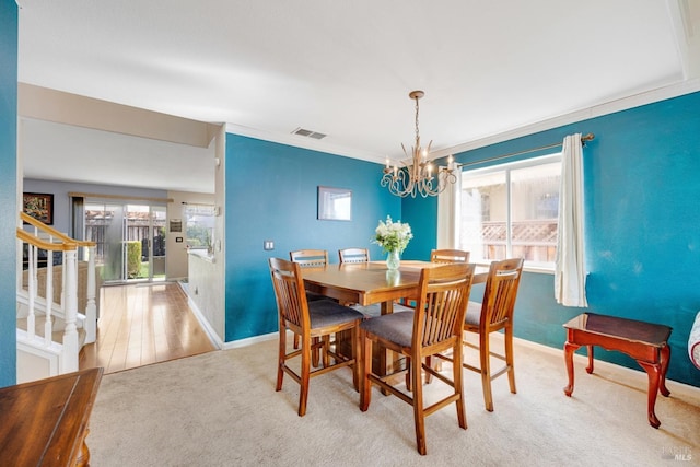 carpeted dining area with a notable chandelier, visible vents, baseboards, stairs, and ornamental molding