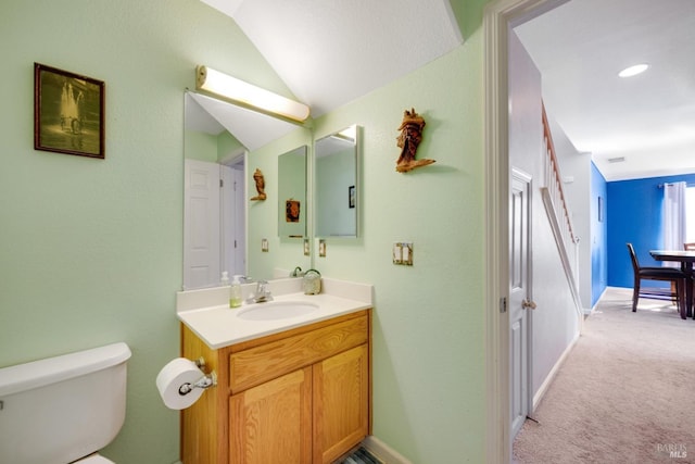 bathroom featuring baseboards, vaulted ceiling, vanity, and toilet