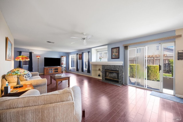 living area with ceiling fan, a fireplace, wood finished floors, and visible vents