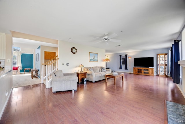 living area with a ceiling fan, a fireplace, stairway, and wood finished floors