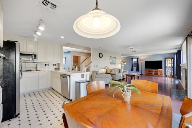 dining area with ceiling fan, light floors, stairway, and visible vents