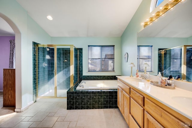 full bathroom featuring a bath, a shower stall, double vanity, and a sink