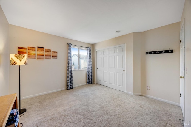 unfurnished bedroom with carpet, a closet, and baseboards