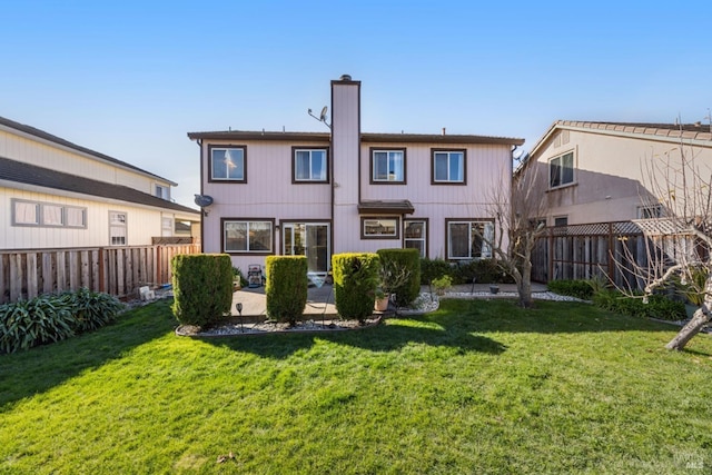 rear view of property featuring a fenced backyard, a chimney, a patio, and a yard