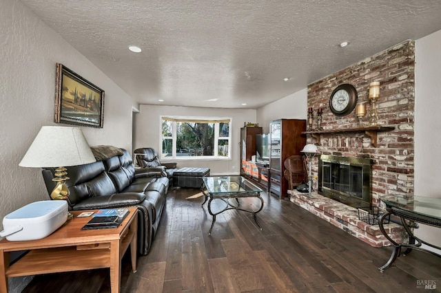 living room with wood-type flooring, a brick fireplace, and a textured ceiling